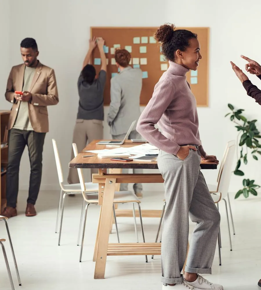 Des collègues en séance de travail collaboratif dans un bureau lumineux, autour d'une table et d'un tableau de notes