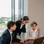 Trois personnes en réunion autour d’un ordinateur portable dans un bureau